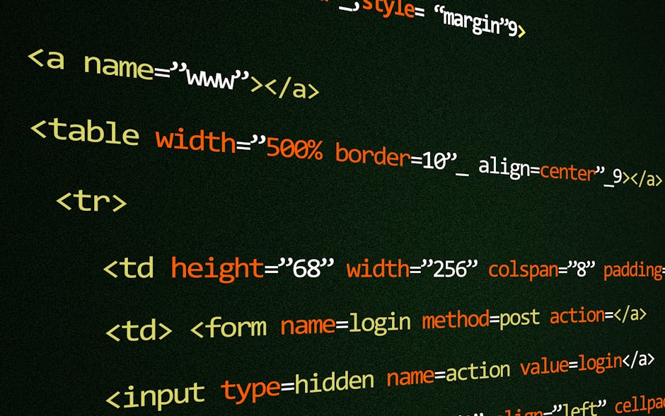 A person working at a desk is focused on a laptop displaying lines of colorful programming code. The individual has short dark hair and is wearing a light blue shirt. The desk is equipped with a compu
